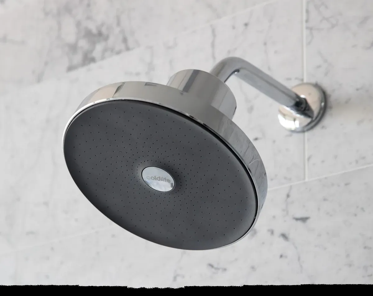 The Ultimate Showerhead installed on a marble bathroom wall